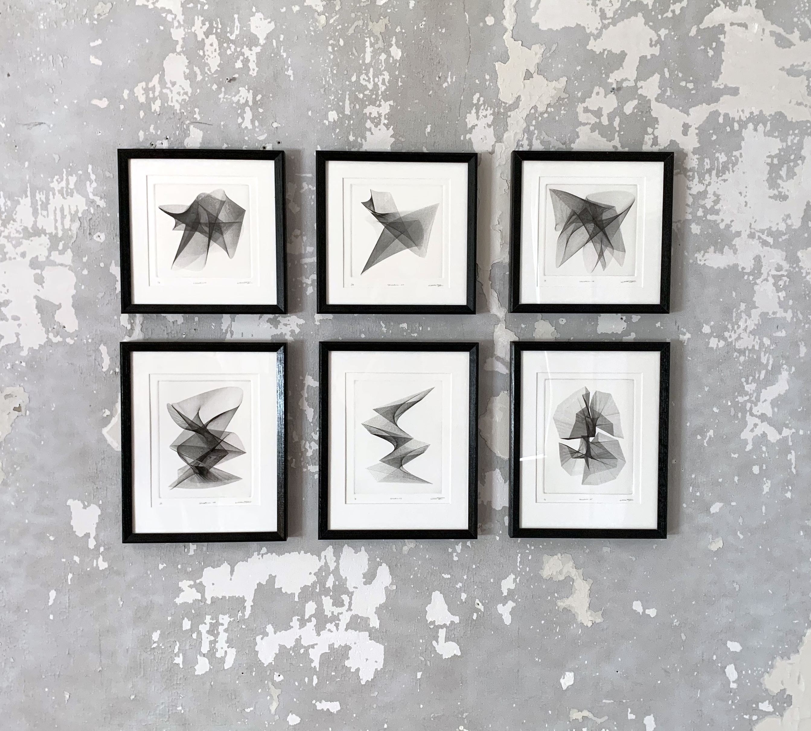 Six framed CNC engravings hung on a concrete wall